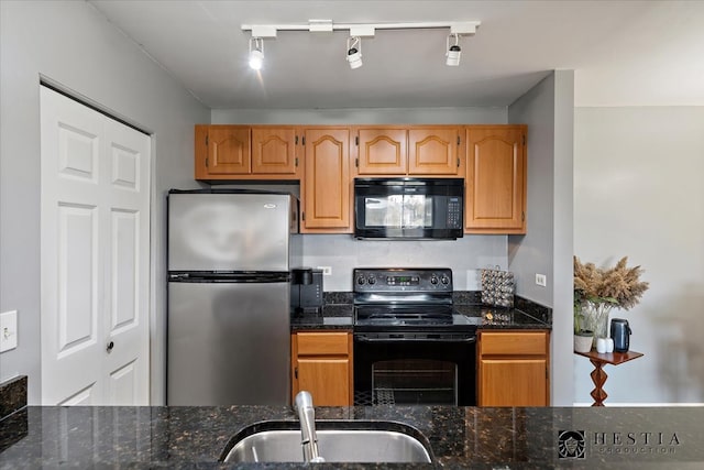 kitchen featuring sink, black appliances, track lighting, and dark stone countertops