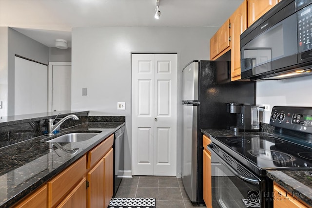 kitchen featuring dark tile patterned floors, dark stone counters, sink, black appliances, and rail lighting