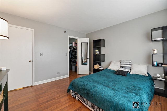 bedroom with a closet, dark hardwood / wood-style floors, and a spacious closet