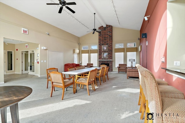 carpeted dining area featuring beamed ceiling, a brick fireplace, high vaulted ceiling, and ceiling fan