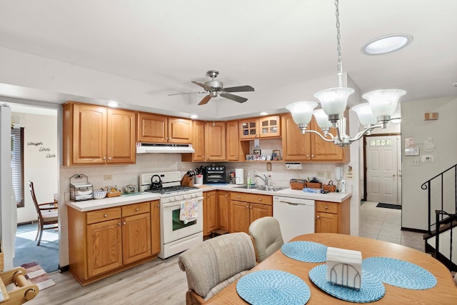 kitchen featuring light wood-type flooring, sink, ceiling fan with notable chandelier, decorative light fixtures, and white appliances