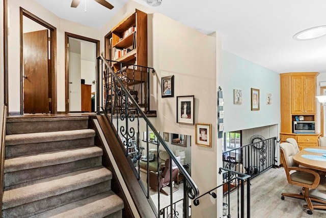 stairs with hardwood / wood-style flooring and ceiling fan