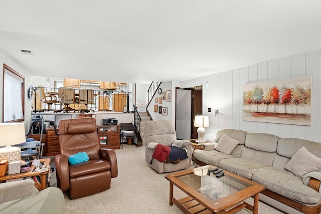 carpeted living room featuring wooden walls