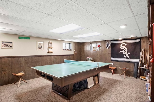 rec room with carpet flooring, a paneled ceiling, and wood walls