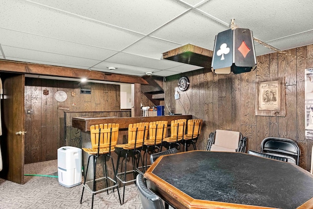 bar with wooden walls, a paneled ceiling, and carpet