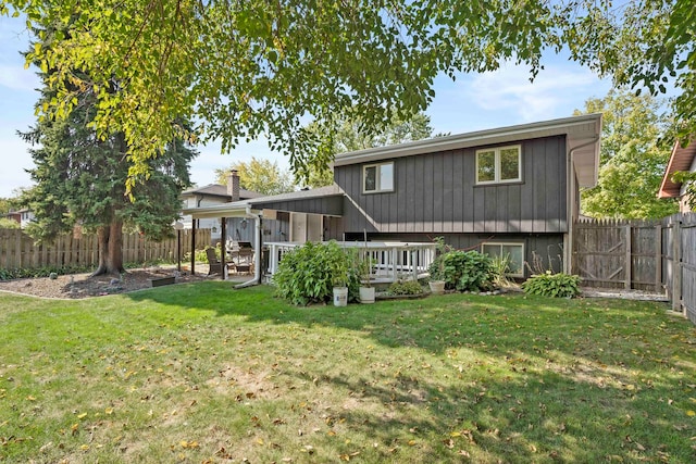 rear view of house featuring a wooden deck and a lawn