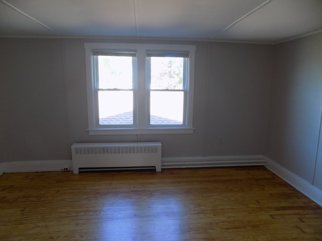 spare room with wood-type flooring, radiator heating unit, and crown molding