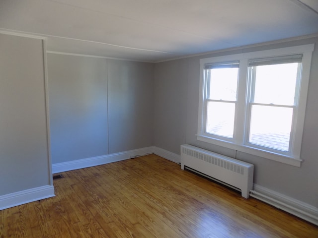 spare room with wood-type flooring, radiator, and crown molding