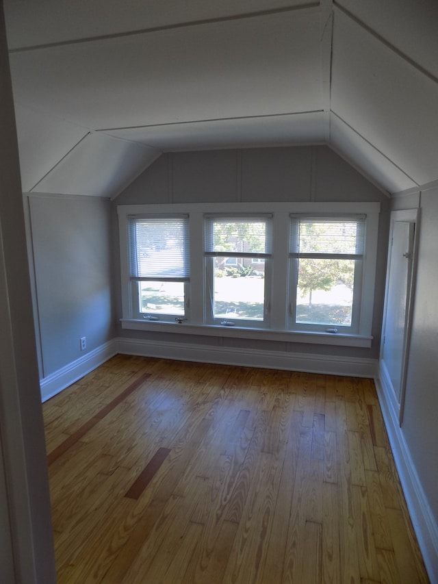 additional living space with hardwood / wood-style flooring and lofted ceiling