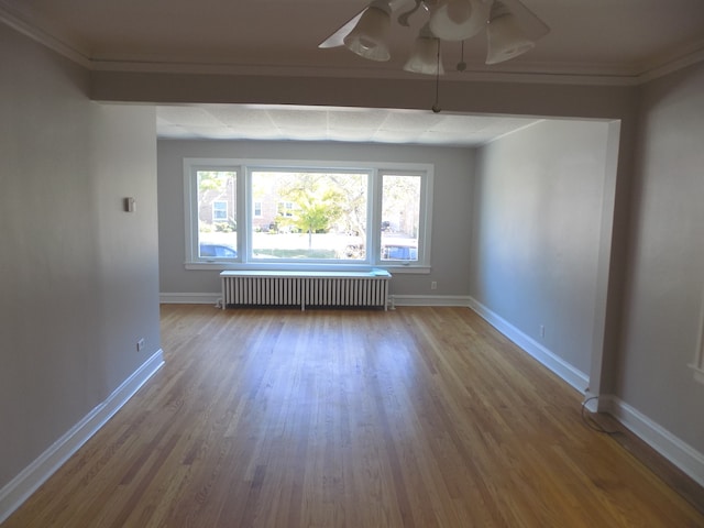 spare room featuring wood-type flooring, radiator, crown molding, and ceiling fan