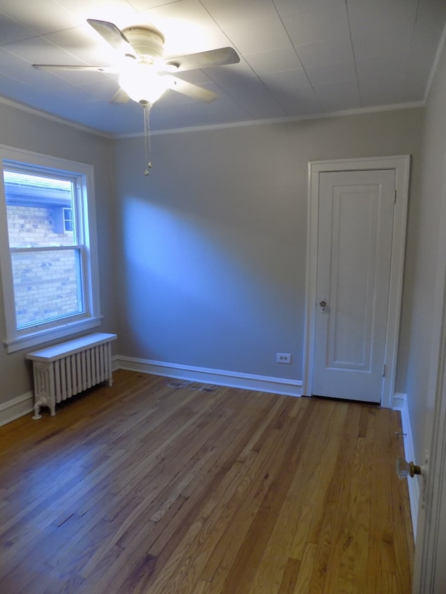 unfurnished room with radiator heating unit, hardwood / wood-style floors, ornamental molding, and ceiling fan