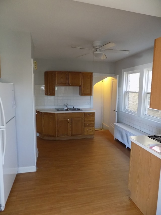 kitchen featuring light wood-type flooring, ceiling fan, sink, decorative backsplash, and white fridge