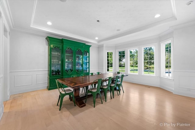 dining room featuring ornamental molding, a tray ceiling, and light hardwood / wood-style floors