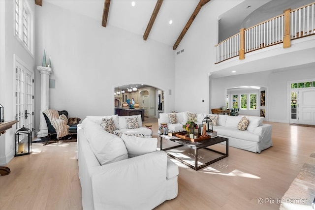 living room with beam ceiling, french doors, high vaulted ceiling, a notable chandelier, and light hardwood / wood-style floors