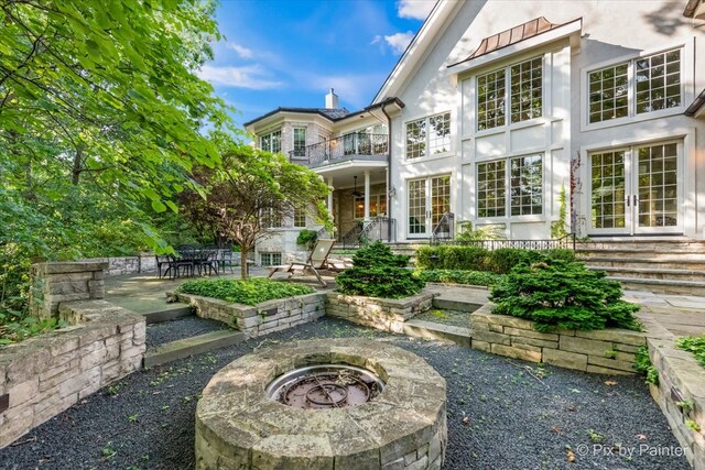 rear view of house featuring french doors, a fire pit, a balcony, and a patio area