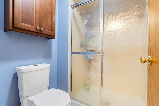 bathroom with a shower with shower door and toilet