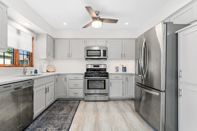 kitchen featuring sink, ceiling fan, appliances with stainless steel finishes, light hardwood / wood-style floors, and decorative backsplash