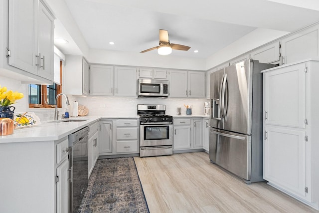 kitchen featuring appliances with stainless steel finishes, sink, light wood-type flooring, and decorative backsplash