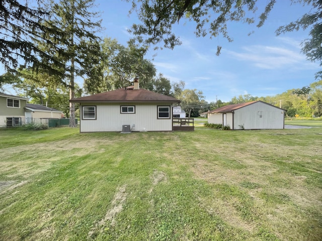 back of house featuring central AC unit and a lawn