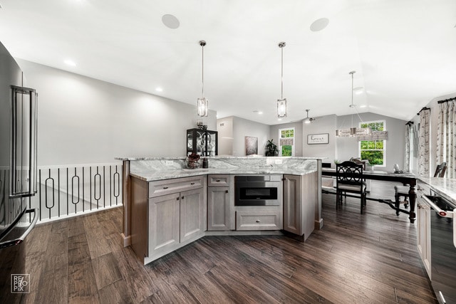 kitchen featuring vaulted ceiling, appliances with stainless steel finishes, decorative light fixtures, and dark wood-type flooring