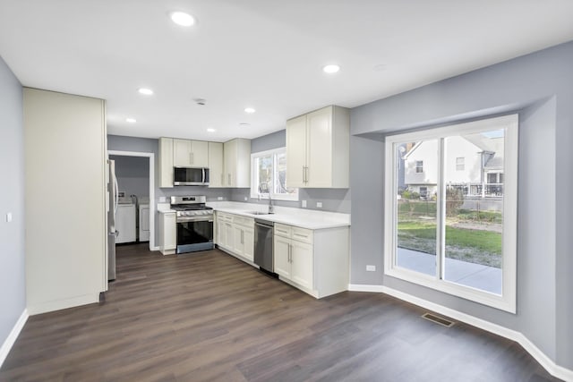 kitchen with baseboards, appliances with stainless steel finishes, dark wood-style floors, and a sink