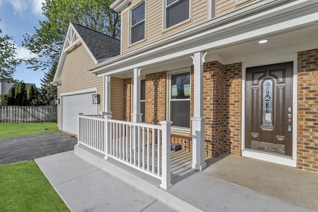 property entrance with covered porch, a shingled roof, aphalt driveway, and brick siding