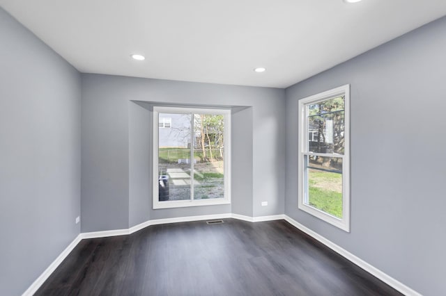unfurnished room with dark wood-style flooring, baseboards, and a wealth of natural light