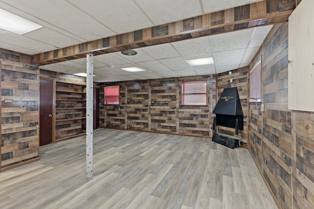 basement featuring wood walls, wood-type flooring, and a drop ceiling