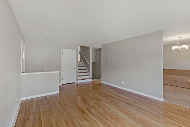 unfurnished room featuring a baseboard radiator, light wood-type flooring, and a chandelier