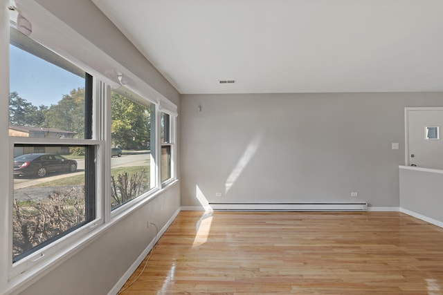 spare room with a baseboard radiator, plenty of natural light, and light hardwood / wood-style floors