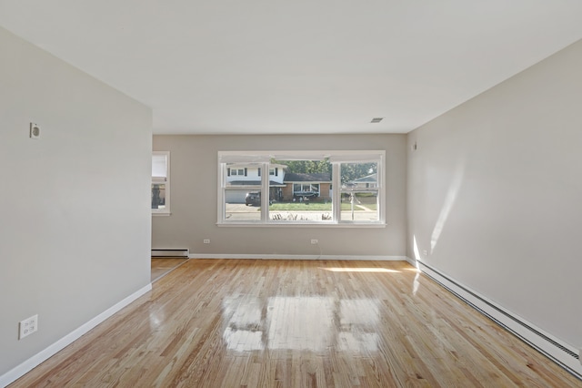 empty room with light wood-type flooring and a baseboard heating unit