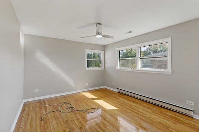 empty room featuring ceiling fan, baseboard heating, and hardwood / wood-style floors