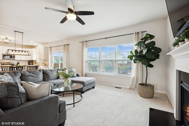 carpeted living room with a healthy amount of sunlight and ceiling fan