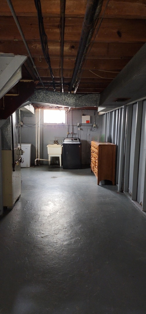 basement featuring washer and clothes dryer, heating unit, and sink