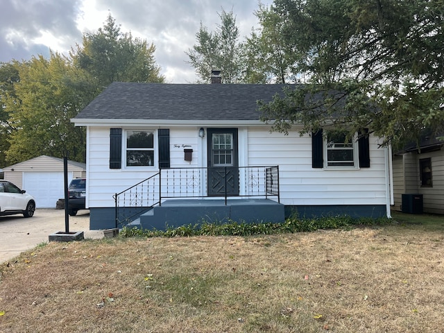 view of front of property featuring an outdoor structure, cooling unit, a front yard, and a garage