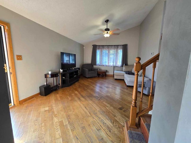 living room featuring hardwood / wood-style floors, ceiling fan, a textured ceiling, and vaulted ceiling