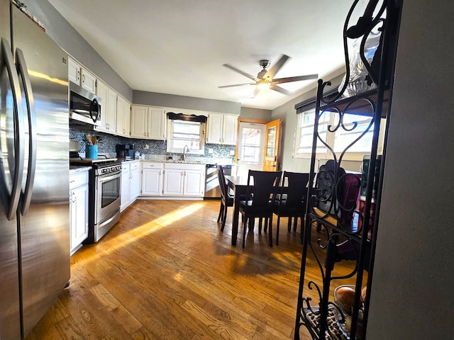 kitchen with a healthy amount of sunlight, stainless steel appliances, wood-type flooring, and decorative backsplash