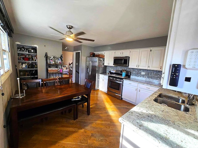 kitchen featuring sink, dark hardwood / wood-style flooring, stainless steel appliances, white cabinets, and light stone counters