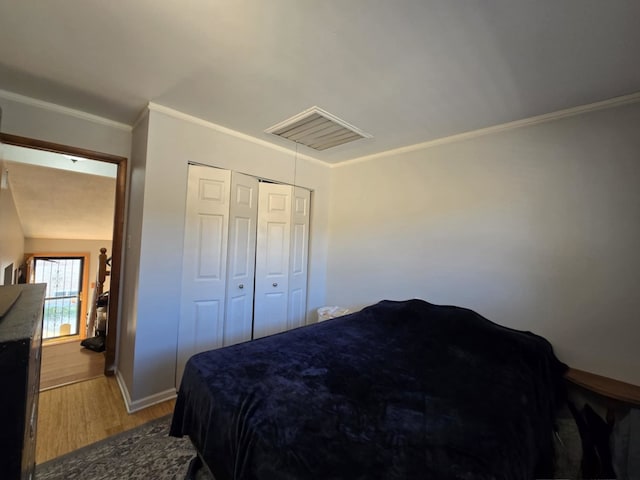 bedroom featuring lofted ceiling, hardwood / wood-style floors, crown molding, and a closet