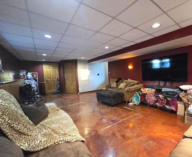 living room with a drop ceiling and concrete flooring