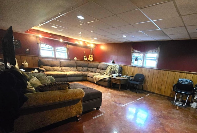 living room featuring wood walls, a wealth of natural light, and a drop ceiling