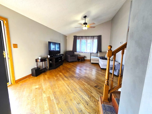 living room with ceiling fan, hardwood / wood-style flooring, a textured ceiling, and vaulted ceiling