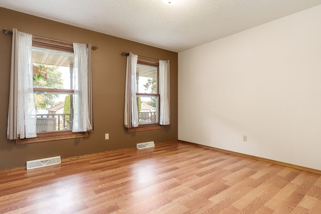 empty room featuring a textured ceiling and light hardwood / wood-style flooring