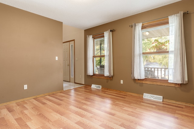 unfurnished room with light wood-type flooring and a textured ceiling