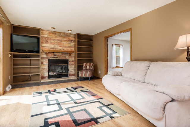 living room with a stone fireplace, hardwood / wood-style flooring, and a textured ceiling