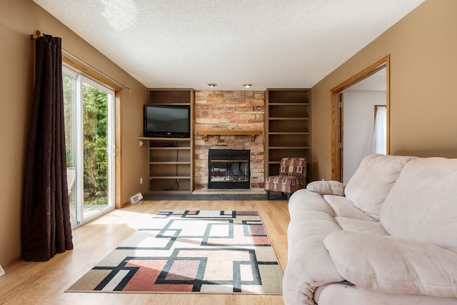 living room with light wood-type flooring, a fireplace, and a textured ceiling