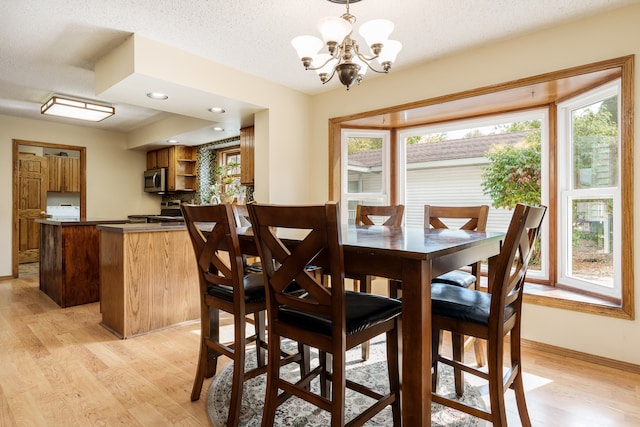 dining space with a textured ceiling, plenty of natural light, light hardwood / wood-style floors, and a chandelier