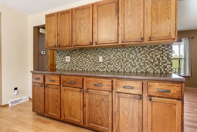 kitchen with a textured ceiling, light hardwood / wood-style flooring, and tasteful backsplash