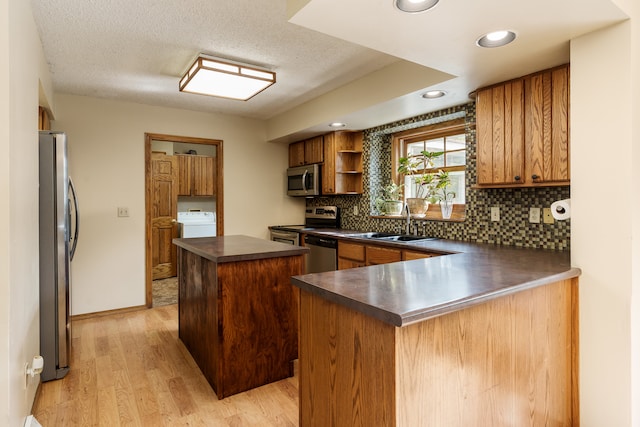 kitchen with a kitchen island, light wood-type flooring, stainless steel appliances, sink, and kitchen peninsula