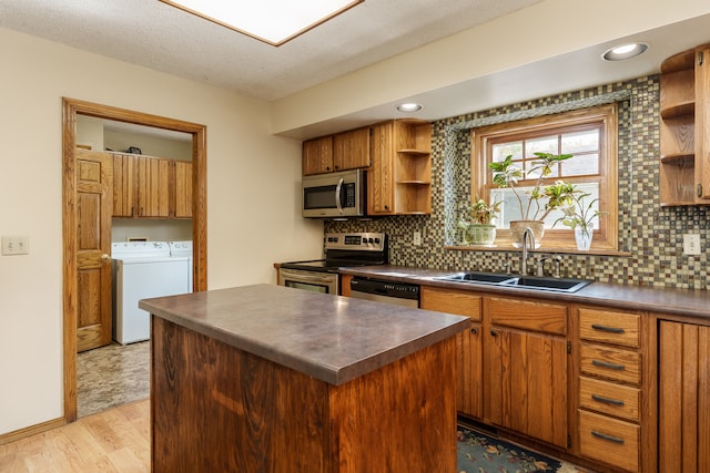 kitchen featuring light hardwood / wood-style flooring, sink, stainless steel appliances, washing machine and dryer, and a center island